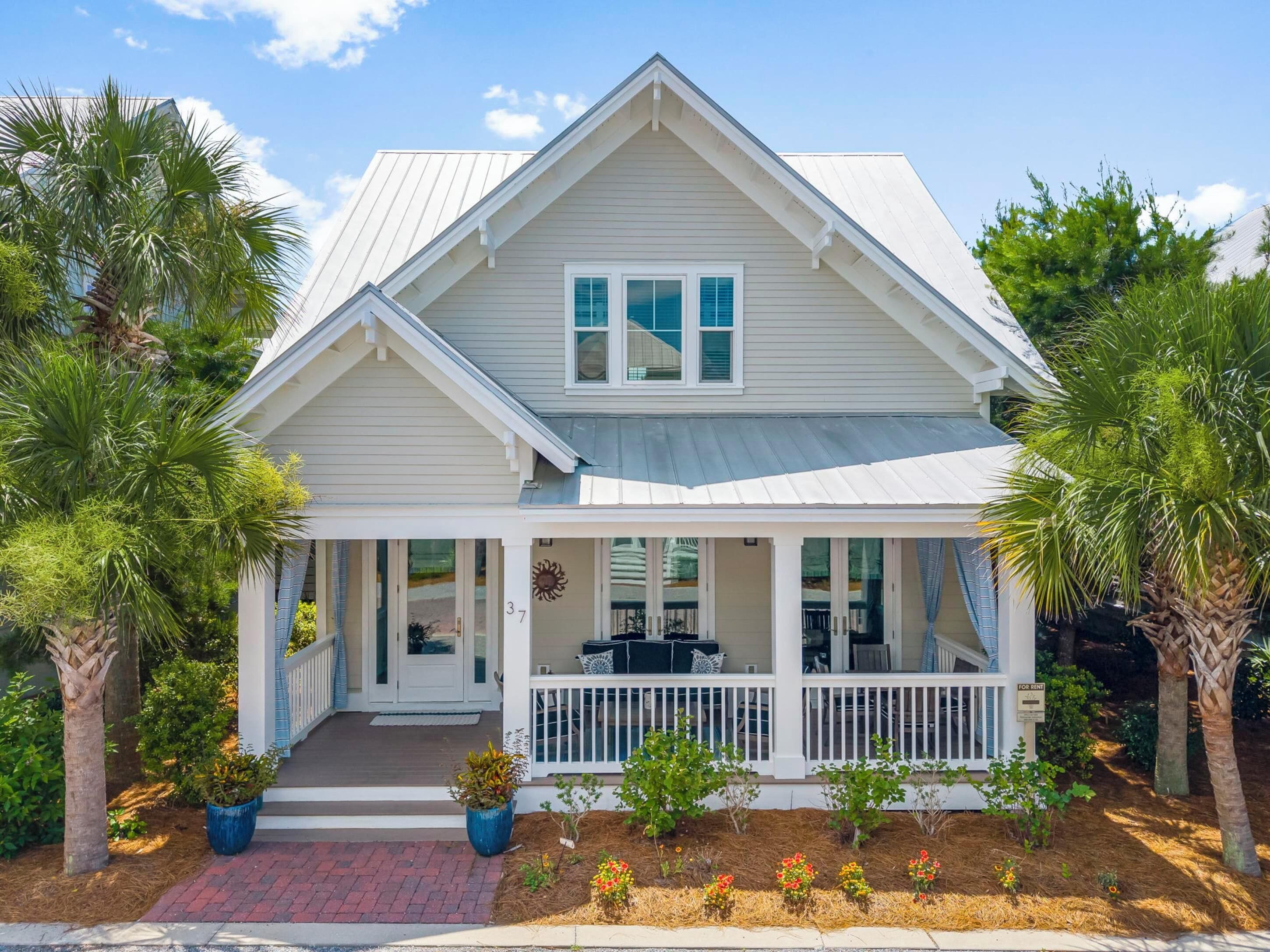 A two-story house with a covered porch, white siding, and a gabled roof.