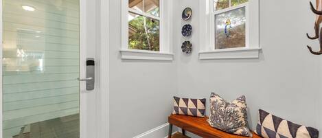 A room with a bench, a glass door, and two windows with decorative plates.