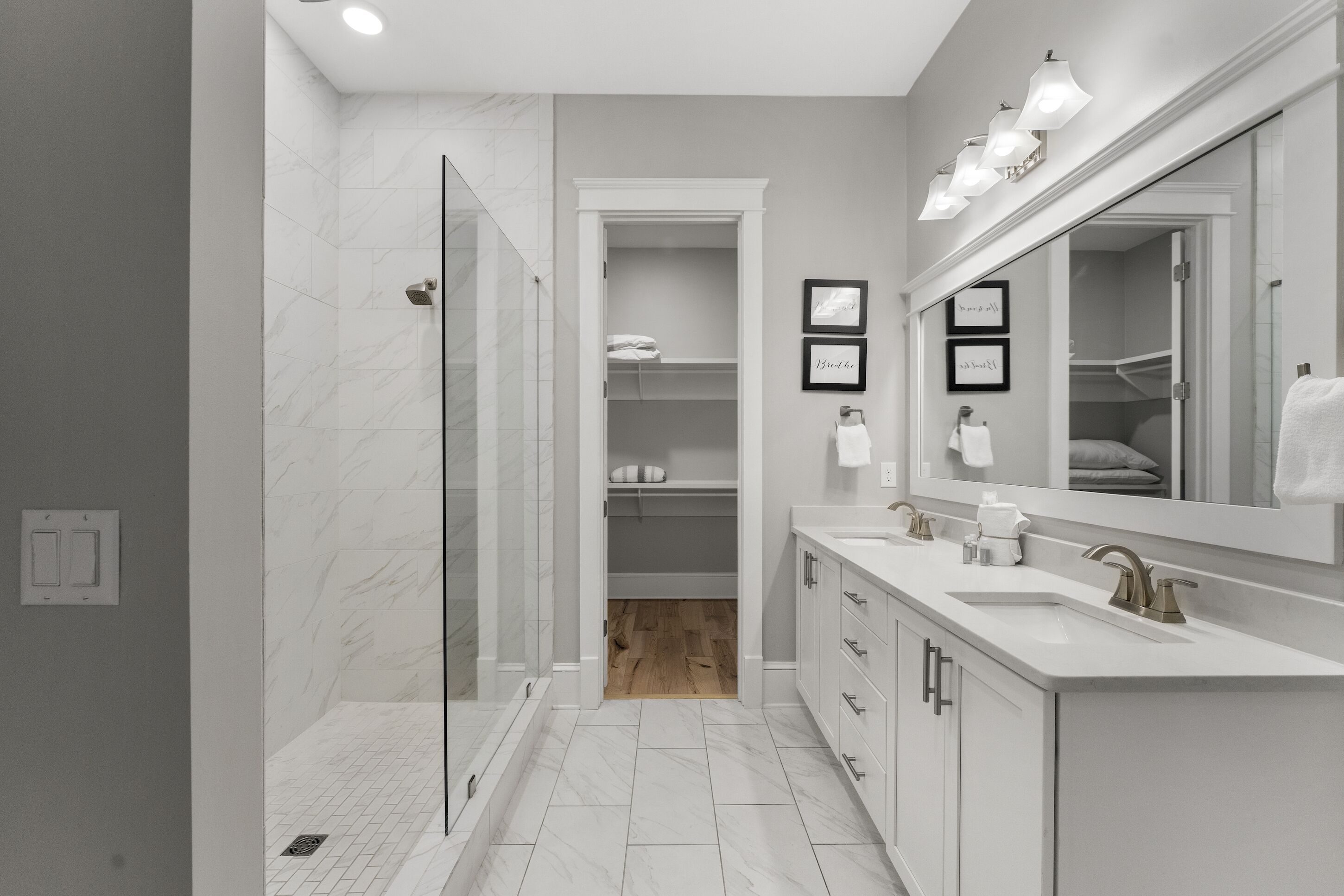 Un baño moderno con ducha a ras de suelo, tocador con un espejo grande y vestidor.
