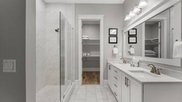 Un baño moderno con ducha a ras de suelo, tocador con un espejo grande y vestidor.
