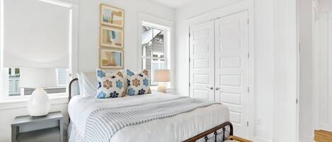 A bedroom with a bed, bedside tables, a bench, a window, and a door.
