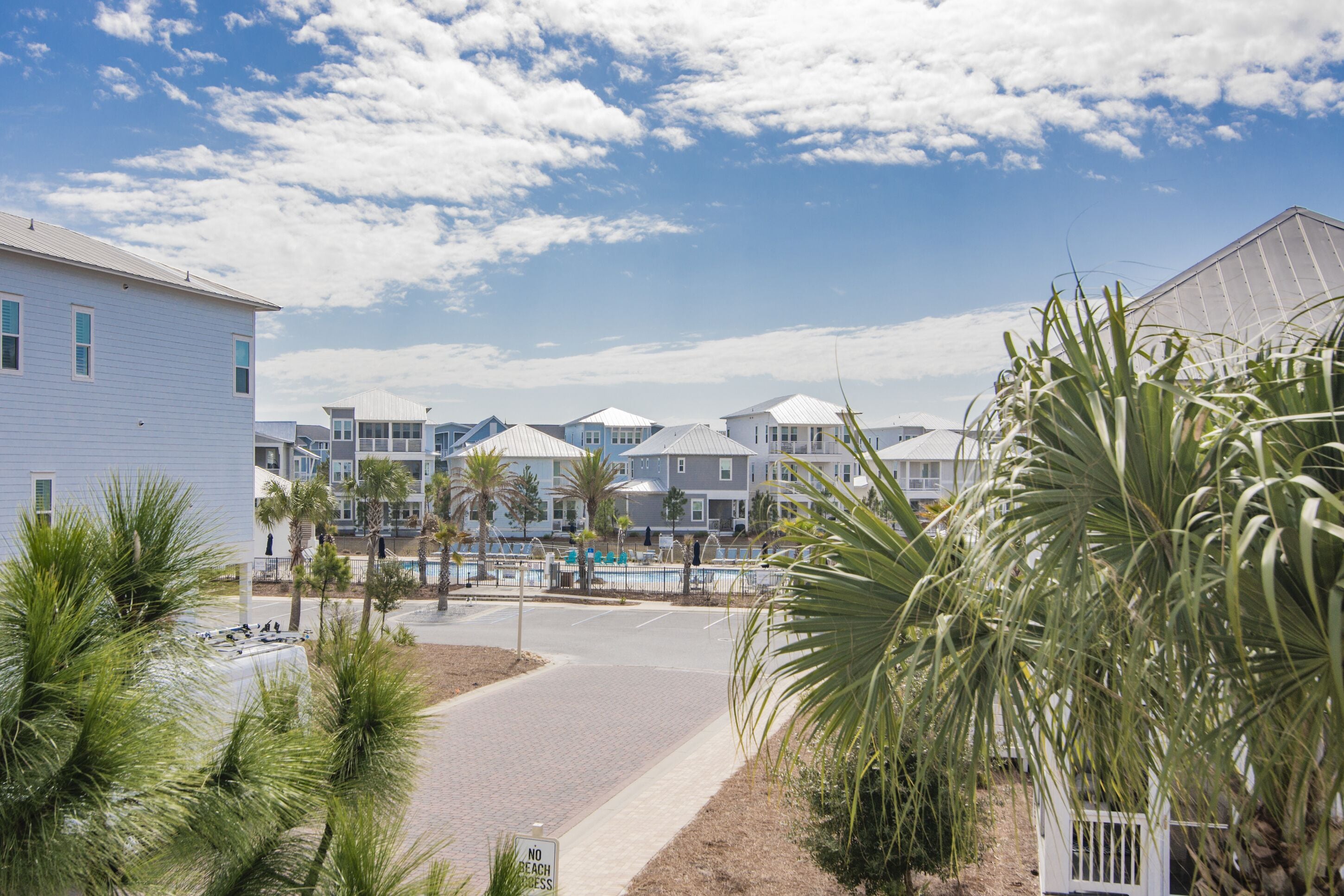 A beachfront hotel with multiple buildings, a swimming pool, and palm trees.