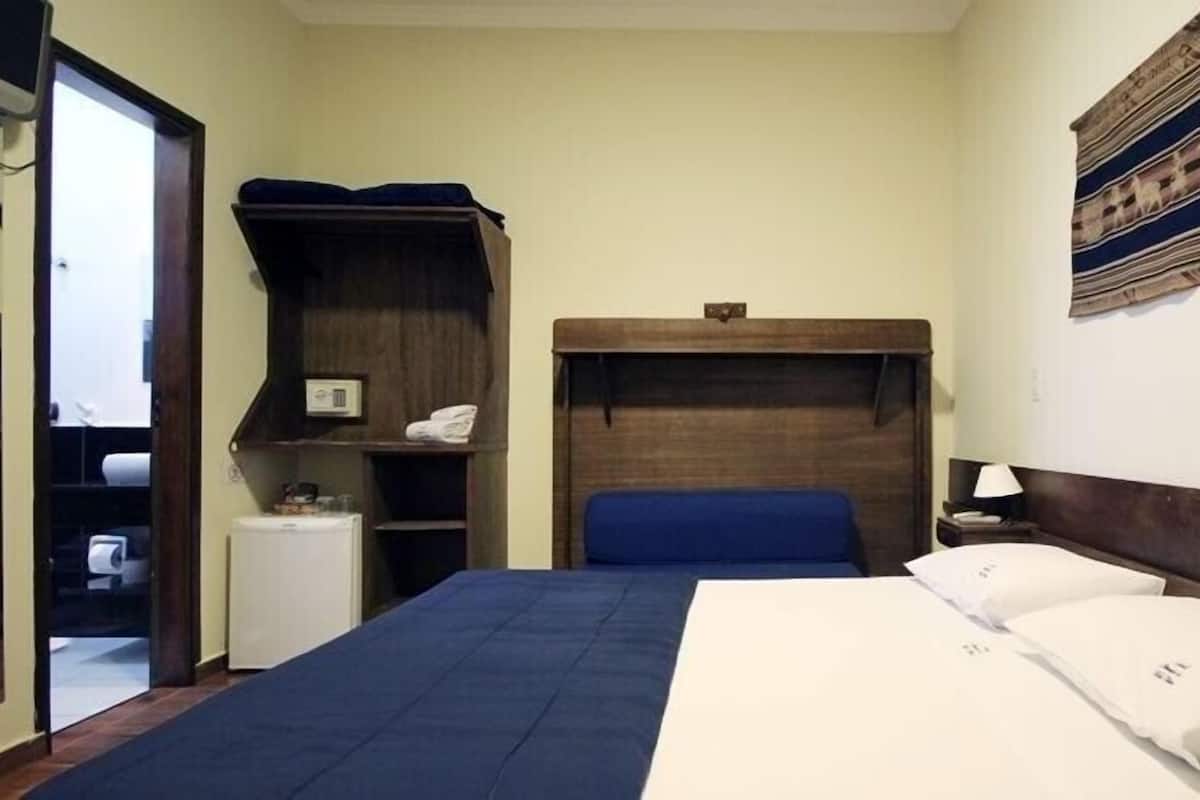 Un dormitorio con cama, armario, mesita de noche pequeña y una obra de arte en la pared.