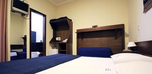 A hotel room with a bed, a bedside table with a lamp, a small shelf with a telephone, and a mirror. - Mirante Praia Hotel (Olímpia)