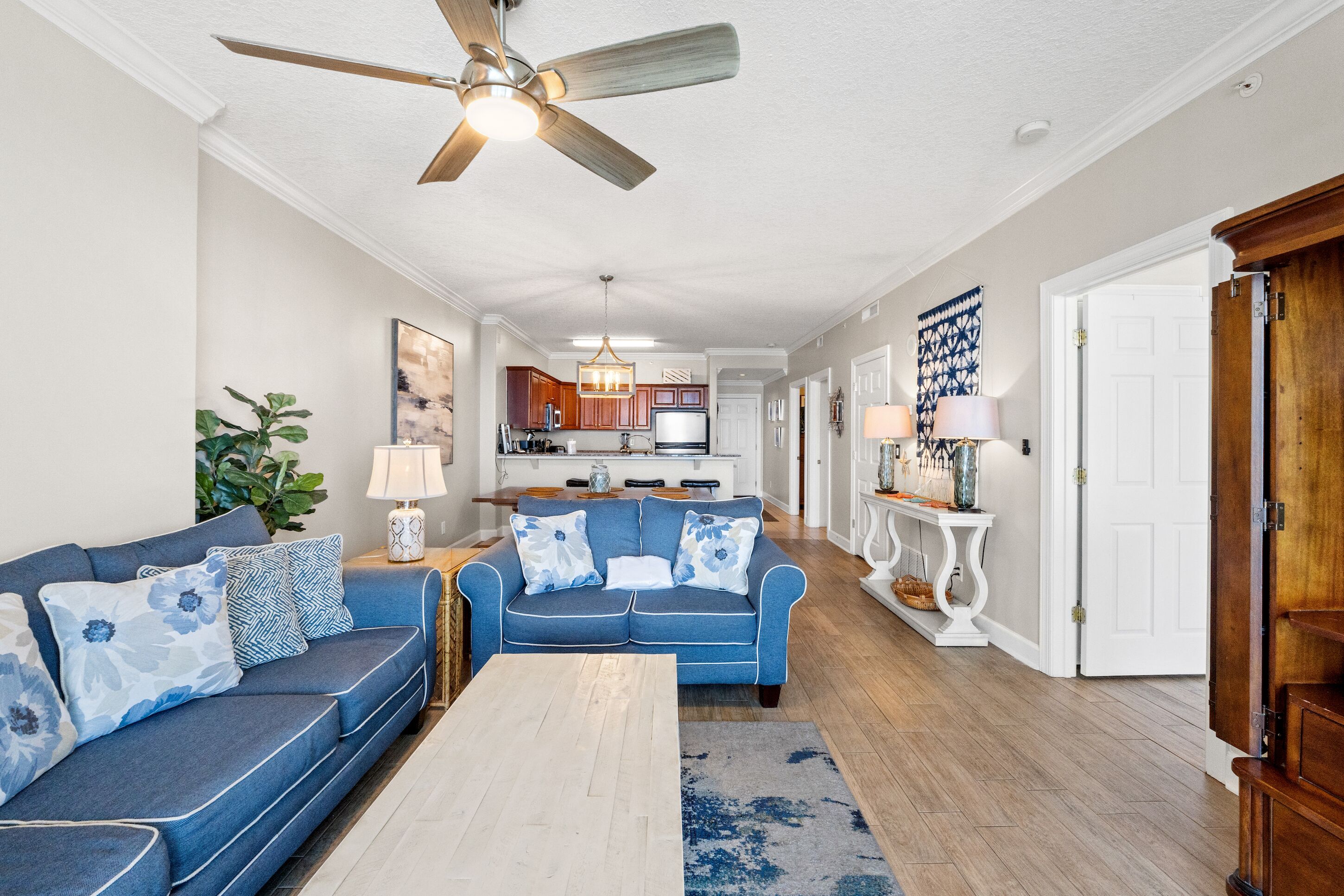 A living room with a blue sofa, a coffee table, and a ceiling fan.