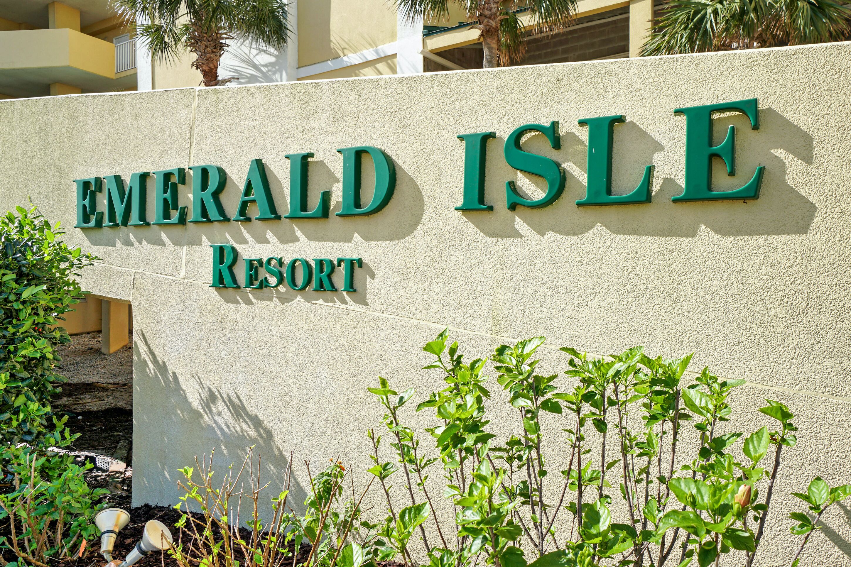 A sign for Emerald Isle Resort with a textured wall and green lettering.