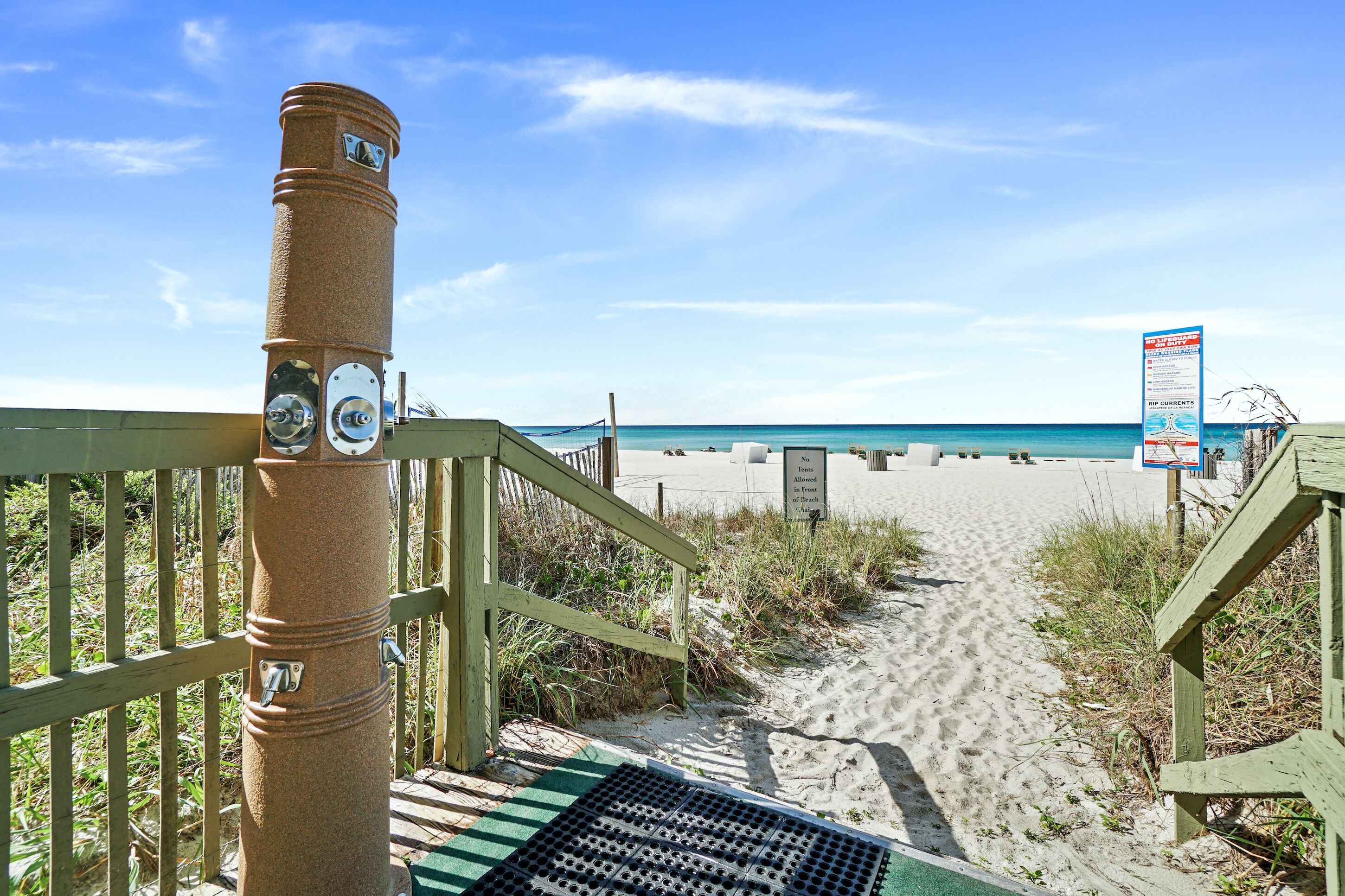 A wooden staircase leading to a sandy beach with a clear blue sky.