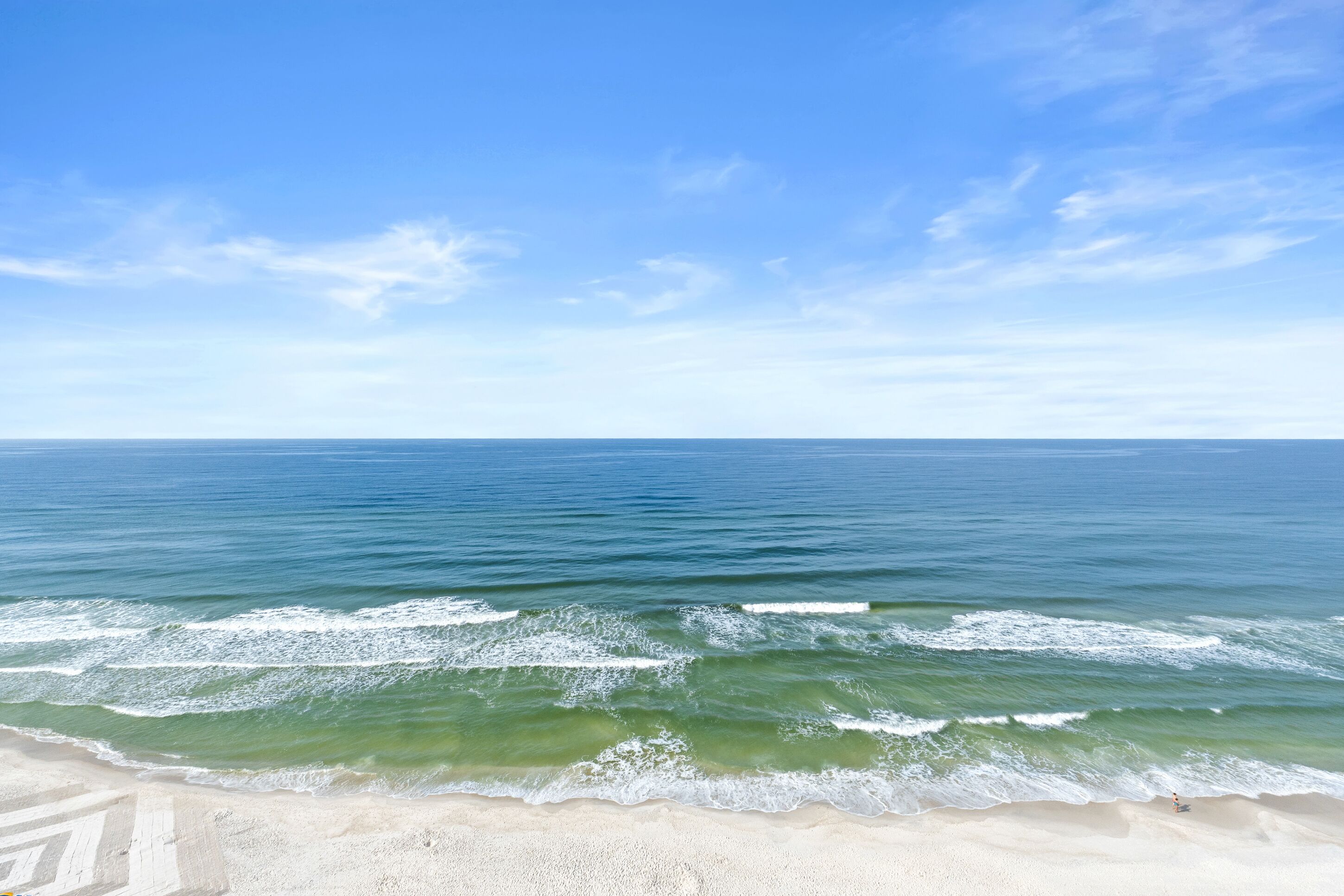 Une plage avec une eau d’un bleu limpide et un rivage sablonneux.