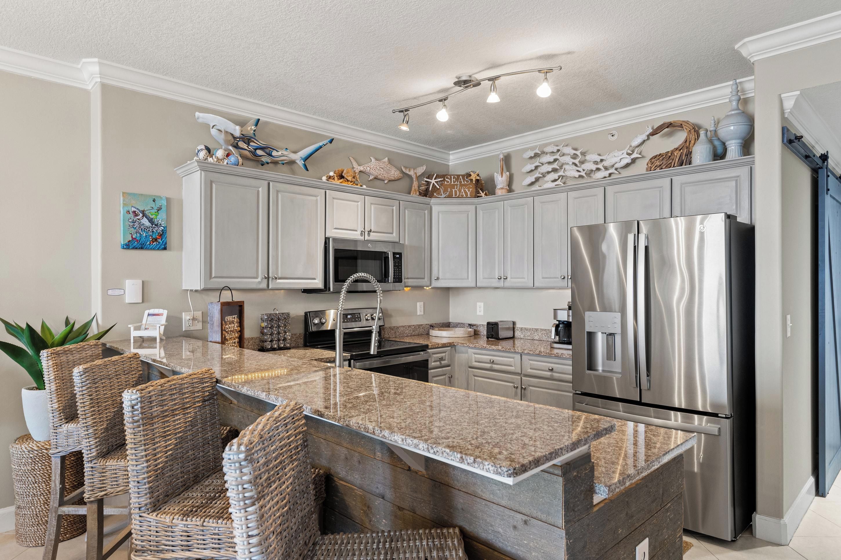 Una cocina moderna con una isla central, electrodomésticos de acero inoxidable y detalles decorativos como un cuadro de peces.