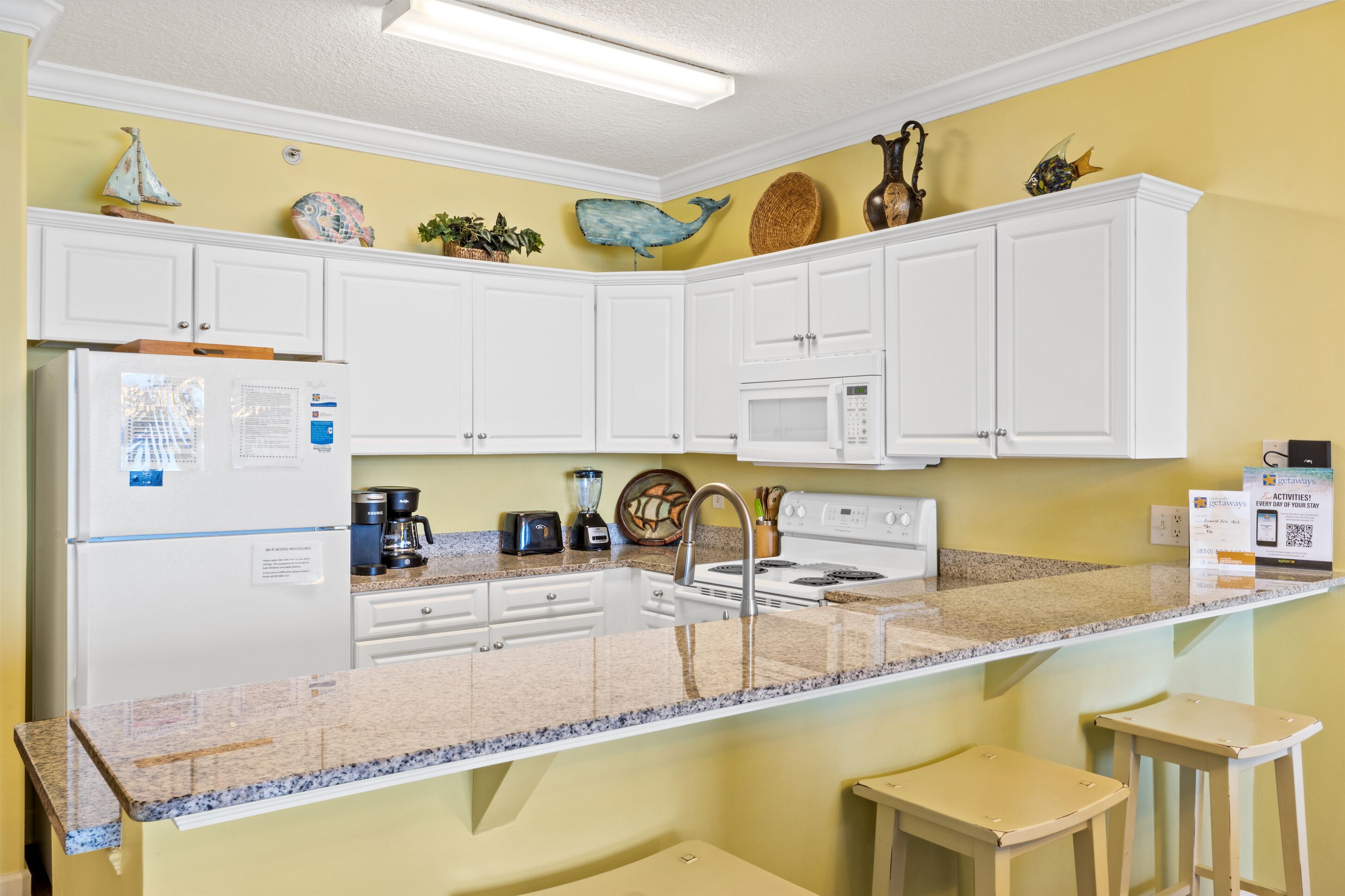 A kitchen with white cabinets, a granite countertop, a refrigerator, a microwave, a stove, and a sink.