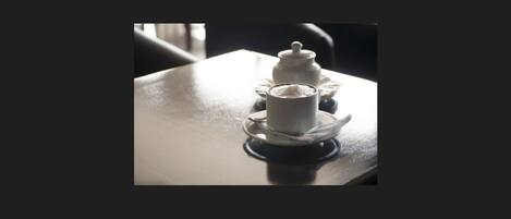 A table with a white teapot and cup on a saucer.