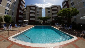 Une piscine rectangulaire dotée d’une rambarde de sécurité en métal, entourée de chaises longues et bordée de briques.
