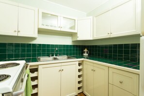A kitchen with white cabinets, a green tiled backsplash, and a white stove. - New Kingston Guest Apartments at Abbey (Kingston)