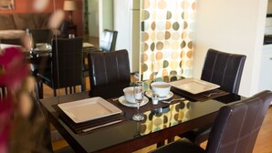 Un espace repas avec une table en verre, des chaises noires et un mur décoratif orné de motifs circulaires.