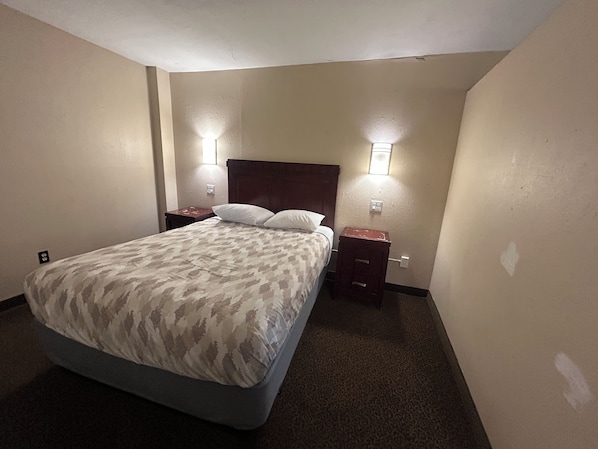 Una camera d'albergo standard con un letto singolo, due comodini e due luci a parete.