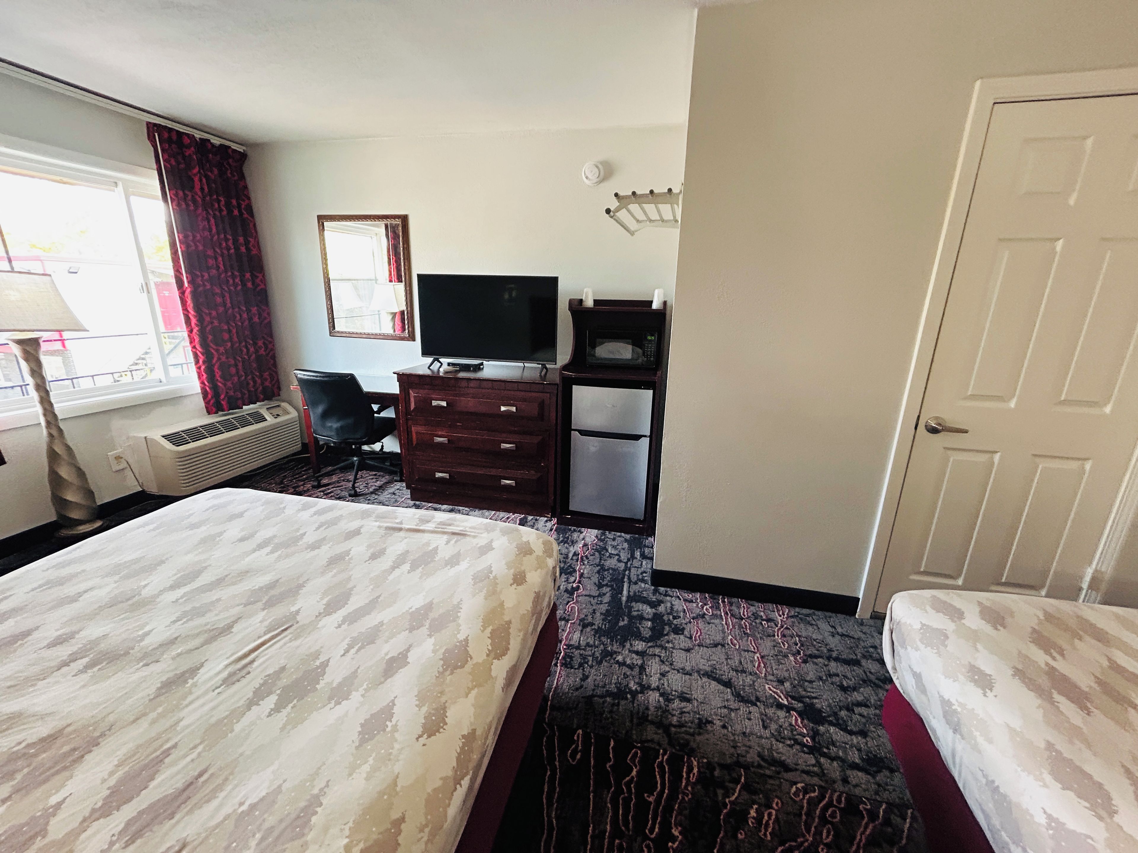 Une chambre d’hôtel comprenant un lit, un bureau avec une télévision, un micro-ondes et une armoire.