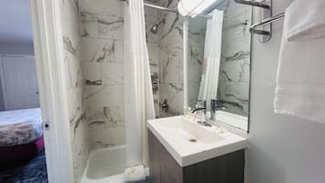 A bathroom with a shower, a sink, and a mirror.