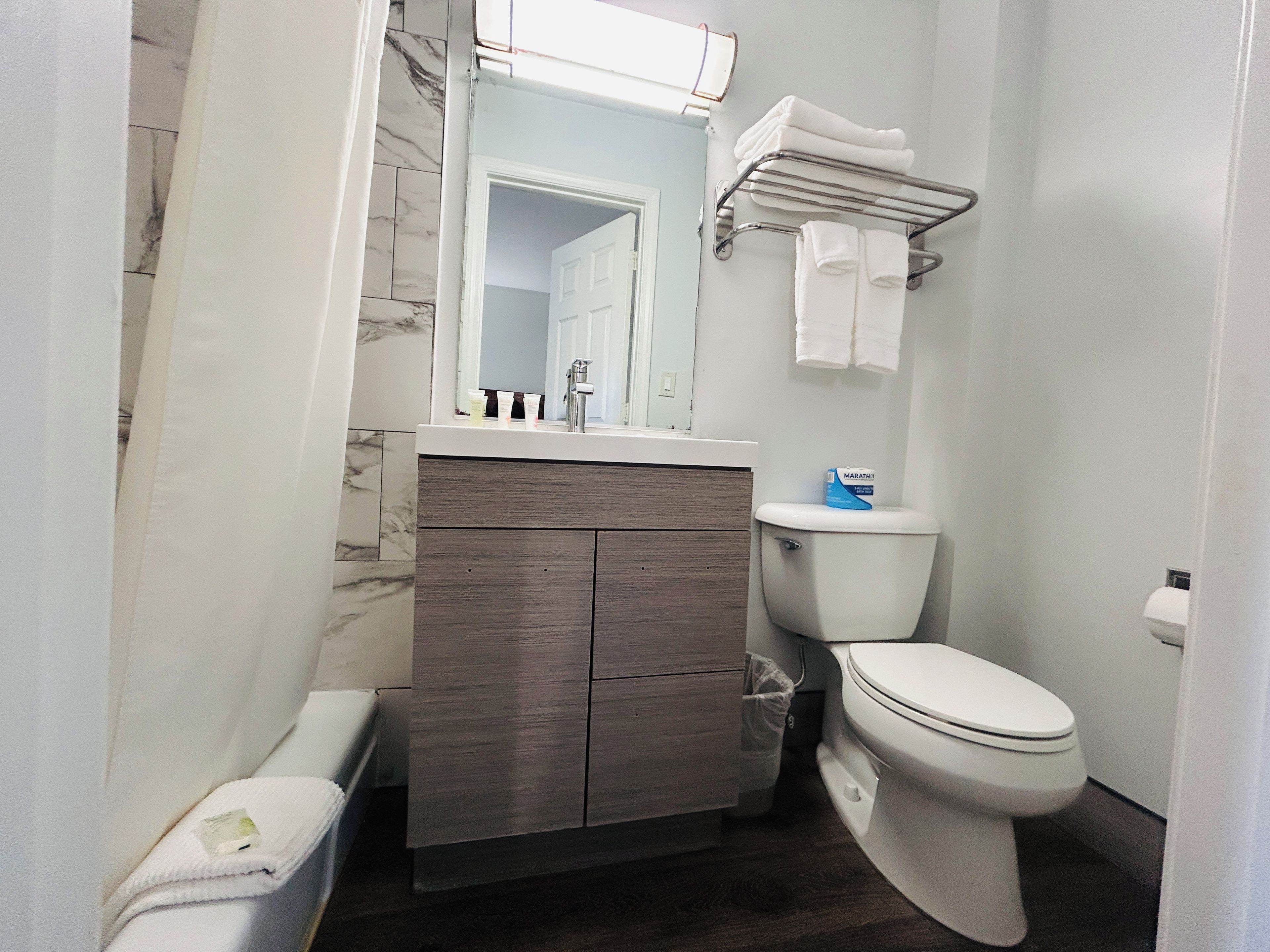 Une salle de bain comprenant des toilettes, un meuble-lavabo avec un miroir et un porte-serviettes.