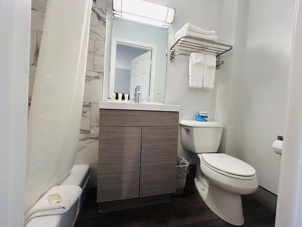Un baño con inodoro, tocador con espejo y perchero para toallas.