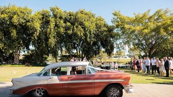 A vintage car parked in a park with a crowd of people in the background.