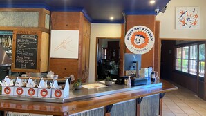 A restaurant counter with a menu for smoothies, a chalkboard with a drawing, and a sign for Buddy Boy Kitchen. - Gidgee Inn Motel (Cloncurry)