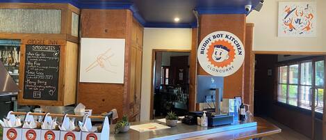 A kitchen counter with a menu for smoothies, a logo for Buddy Boy Kitchen, and a chalkboard with a drawing.