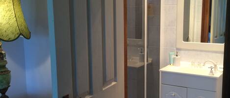 A bathroom with a shower, sink, and mirror.