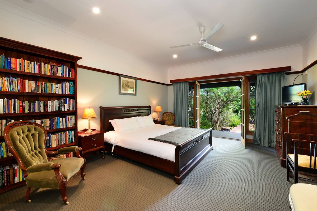 Une chambre à coucher avec un grand lit, une bibliothèque en bois, une chaise, un bureau et un téléviseur.