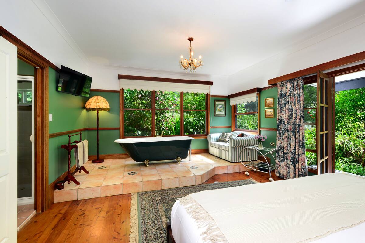 Une salle de bain avec une baignoire sur pieds, un meuble-lavabo et une grande fenêtre.