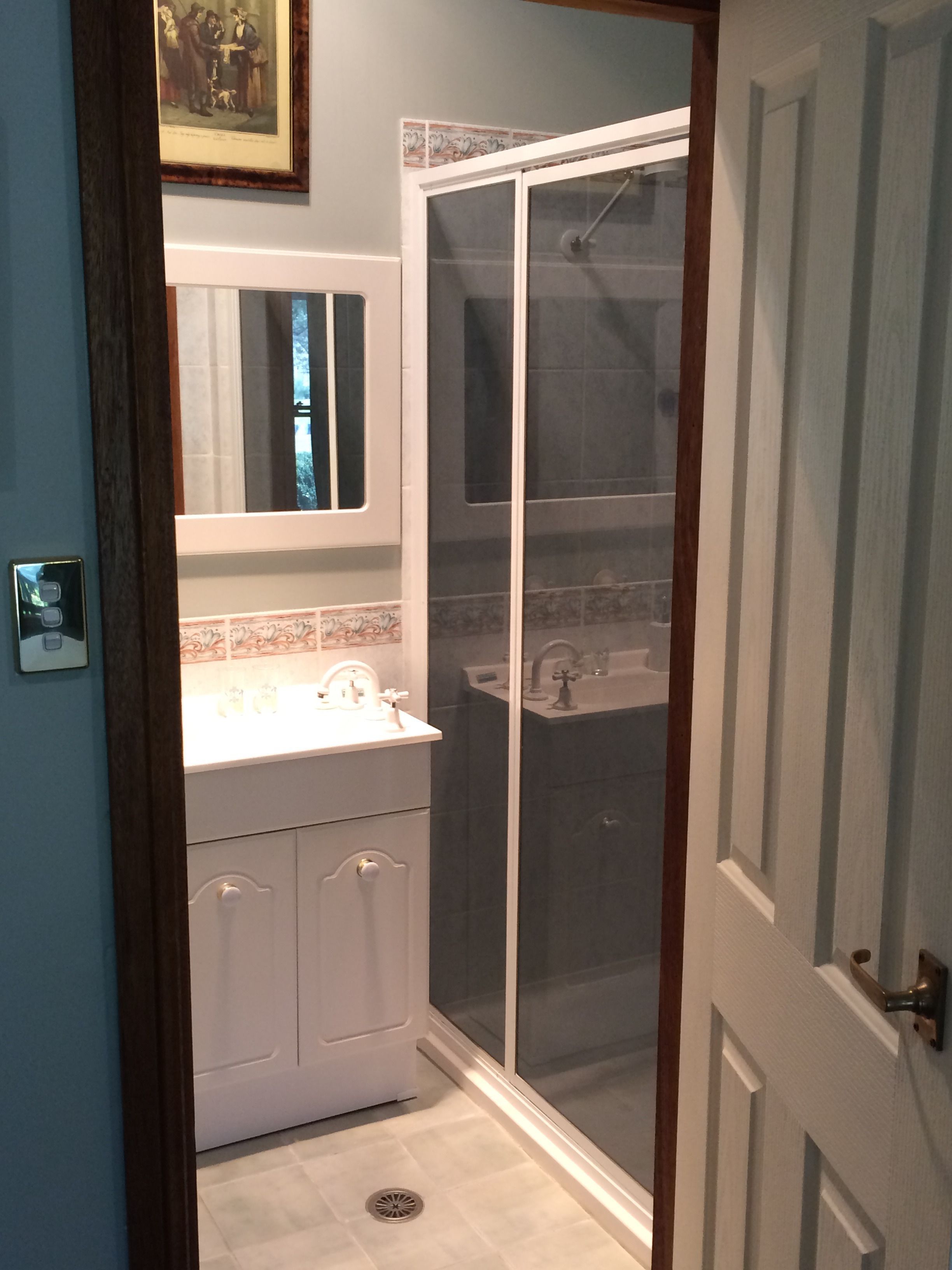 A bathroom with a shower enclosure, a sink, and a mirror.