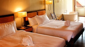 A hotel room with two beds, a ceiling fan, a large window, and a bathtub. - Bravo Resorts - Munting Paraiso (Dauin)