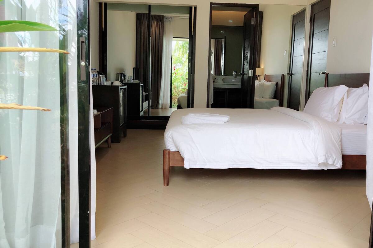 Ein Hotelzimmer mit einem Bett, einem Schreibtisch, einem Spiegel und einem durch eine offene Tür einsehbaren Badezimmer.