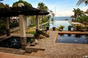 Ein Poolbereich mit einer Pergola, Steintreppe und Topfpflanzen.