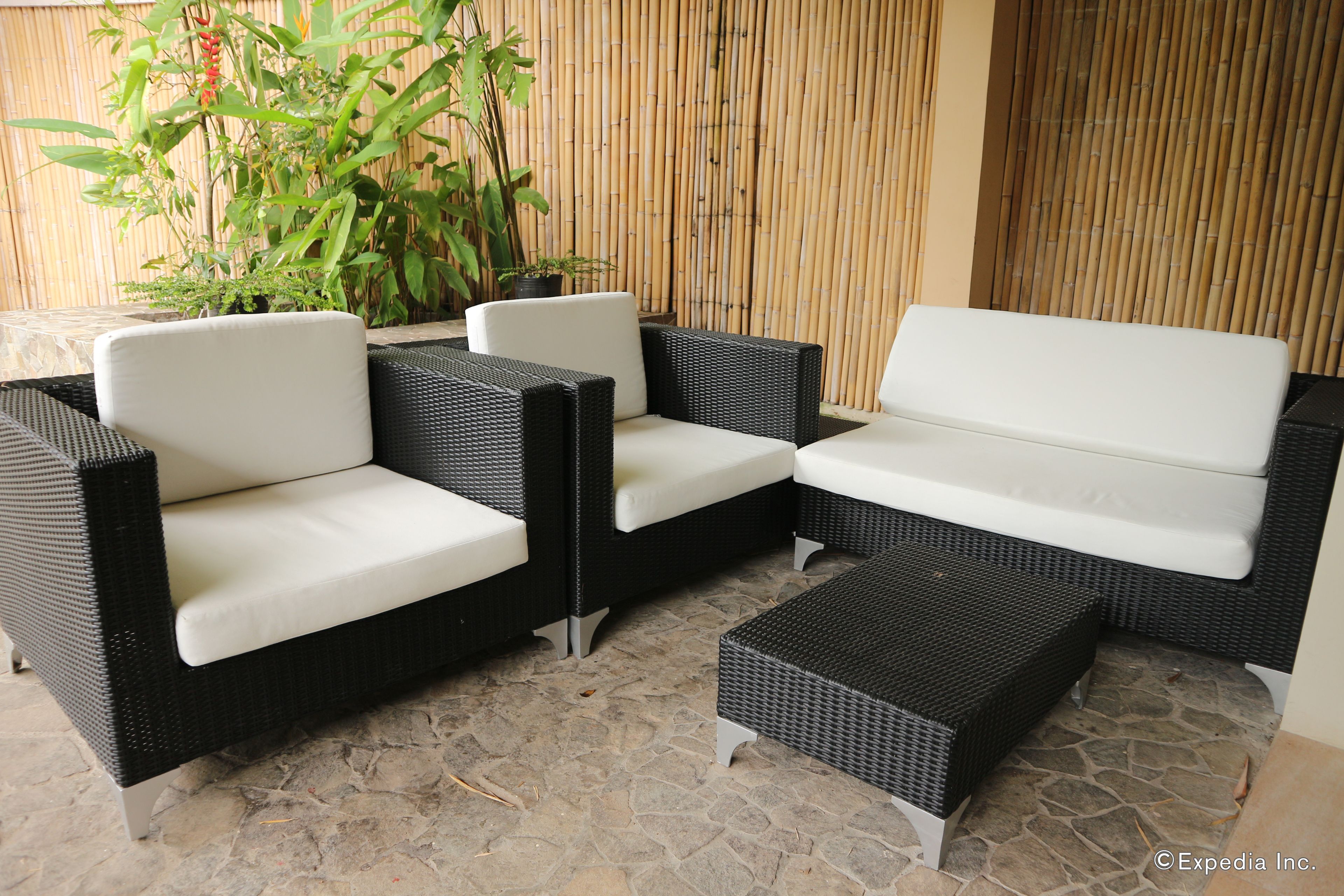 A section of outdoor seating with wicker furniture and a stone floor.
