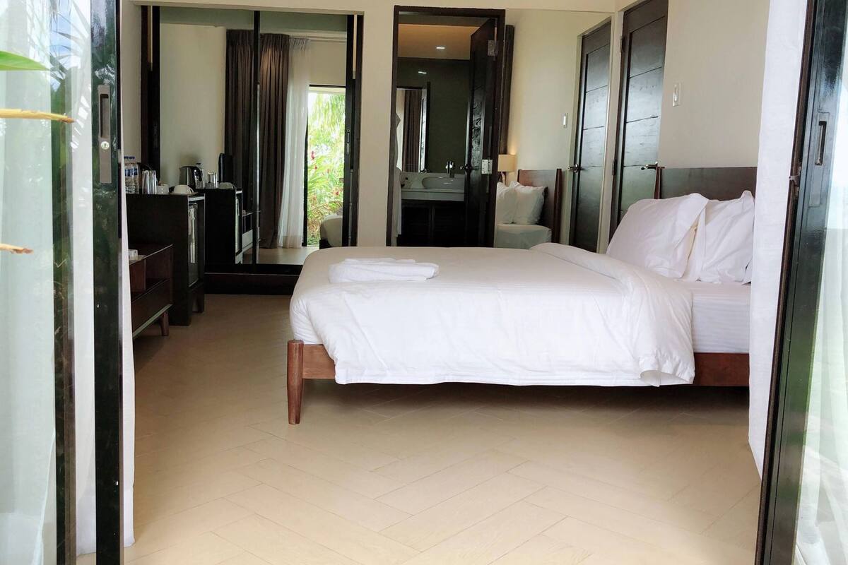 Ein Hotelzimmer mit Bett, Schreibtisch, Spiegel und Badezimmer.
