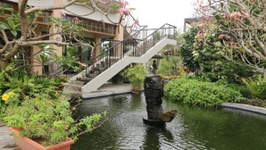 A tranquil garden with a water feature, a staircase, and lush greenery. - Bravo Resorts - Munting Paraiso (Dauin)