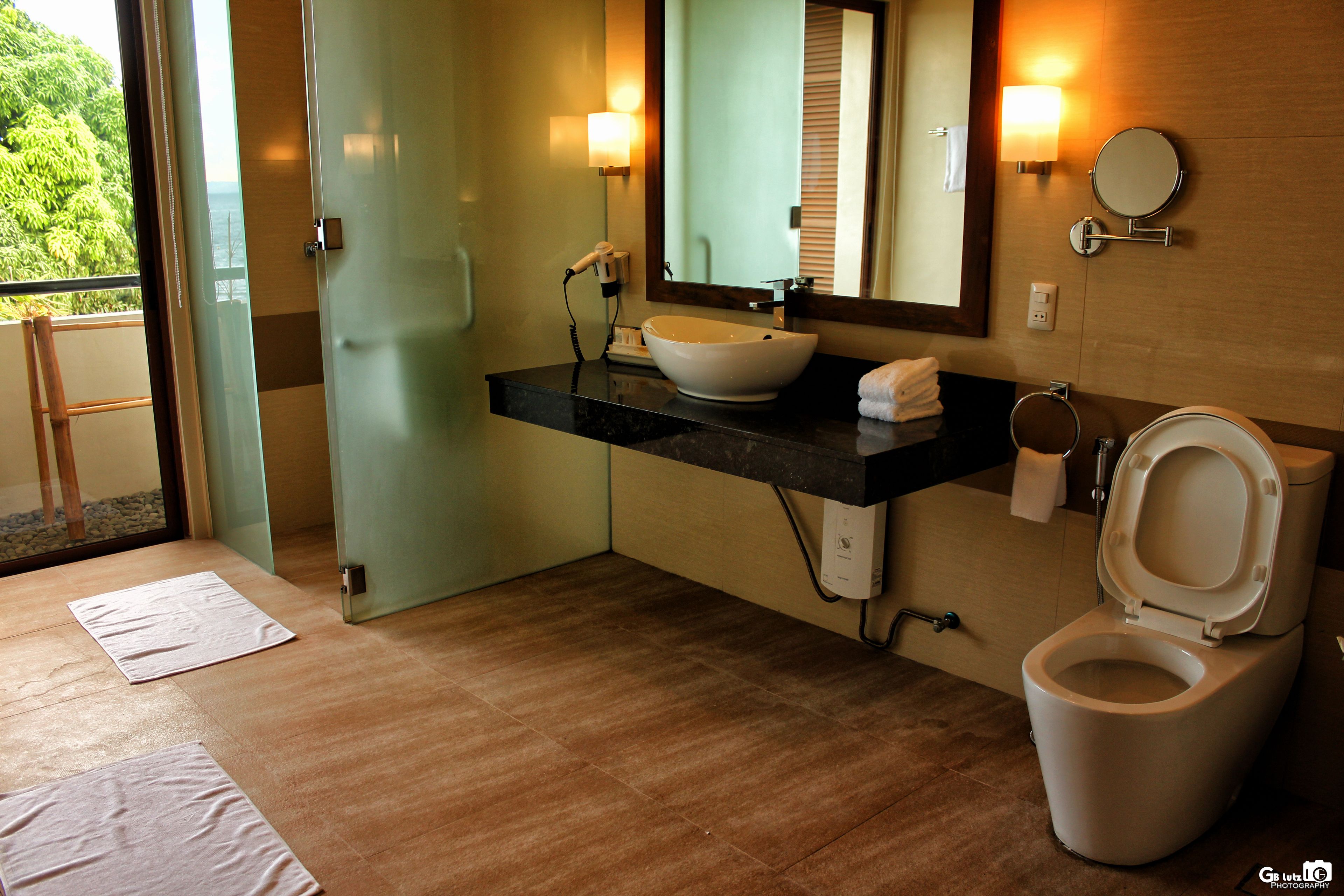 Un baño con un espejo grande, un lavabo y un inodoro.
