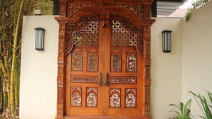 A wooden door with intricate carvings and glass panels. - Bravo Resorts - Munting Paraiso (Dauin)