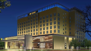 A modern hotel with a prominent entrance, multiple floors, and a rooftop terrace. - Shanghai Pudong Theme Park Wassim Hotel (Shanghai)