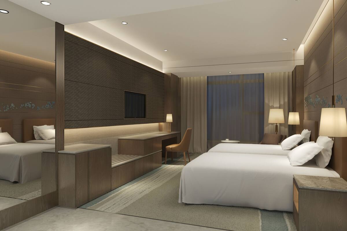 Habitació d'hotel moderna amb dos llits, una taula de treball i zona de seients.