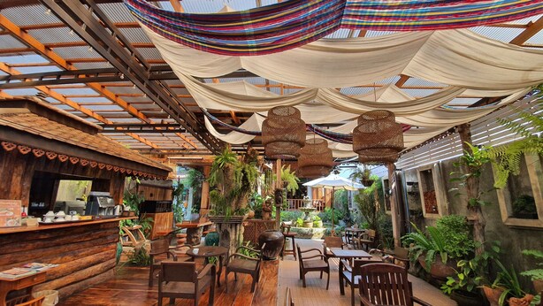 A rustic wooden interior with a bar area, wooden furniture, and hanging plants. - Baan Krittika (Udon Thani)