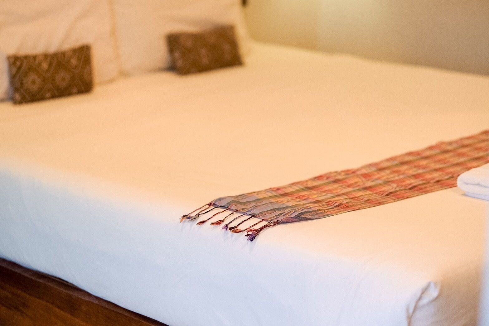 Un lit bien fait, avec un couvre-lit à motifs et des coussins.