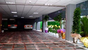 Una zona de estacionamiento techada con piso de baldosas y un automóvil estacionado a lo lejos.
