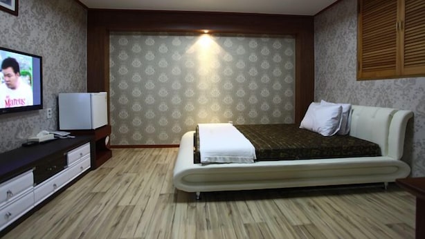 Un dormitorio con cama, televisión, mesita de noche y armario.