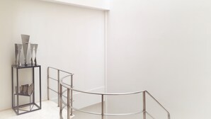 Un interior minimalista con una escalera, barandilla de metal y una lámpara en el techo.