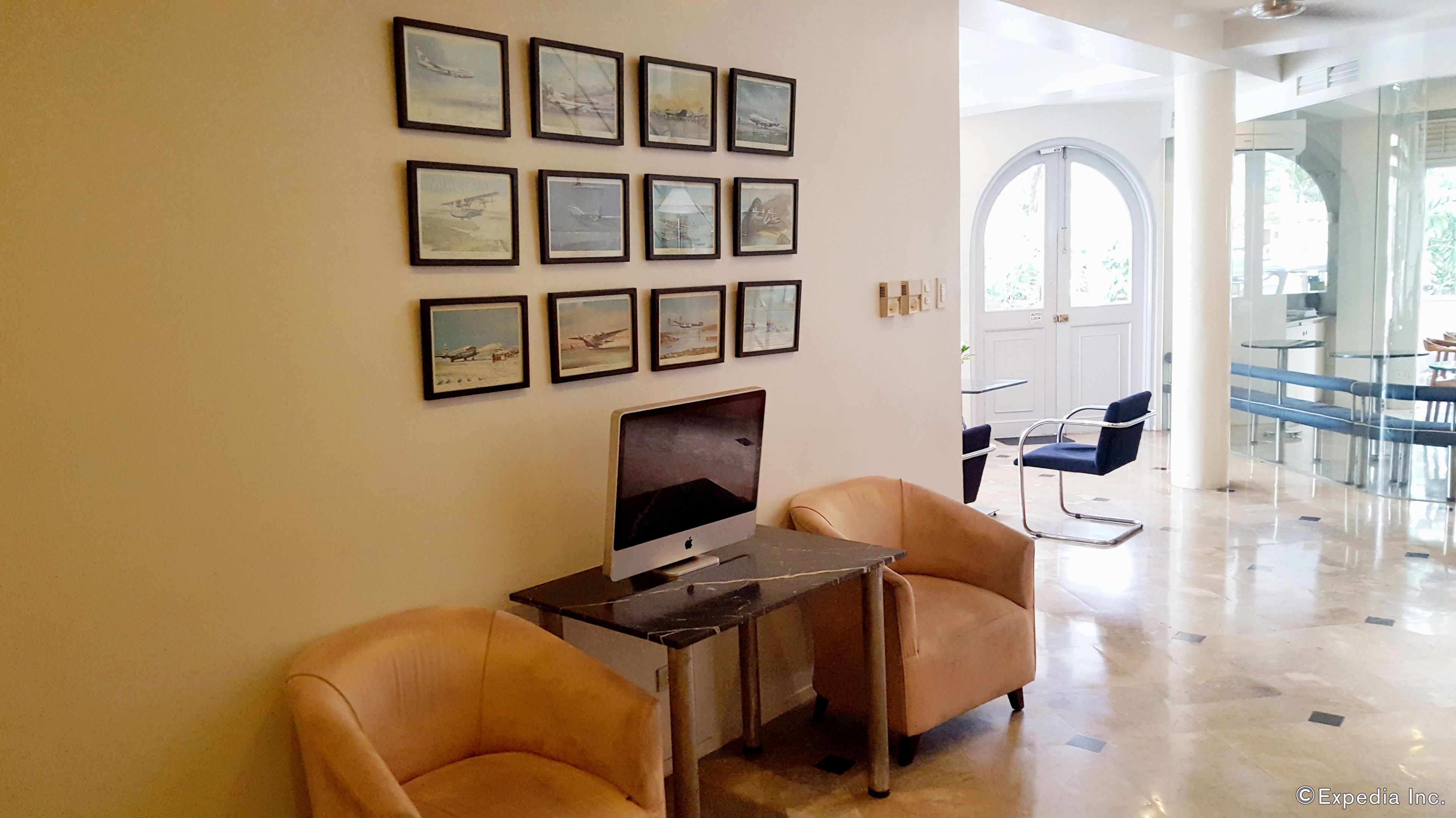 A room with a desk, two leather chairs, and a large window.