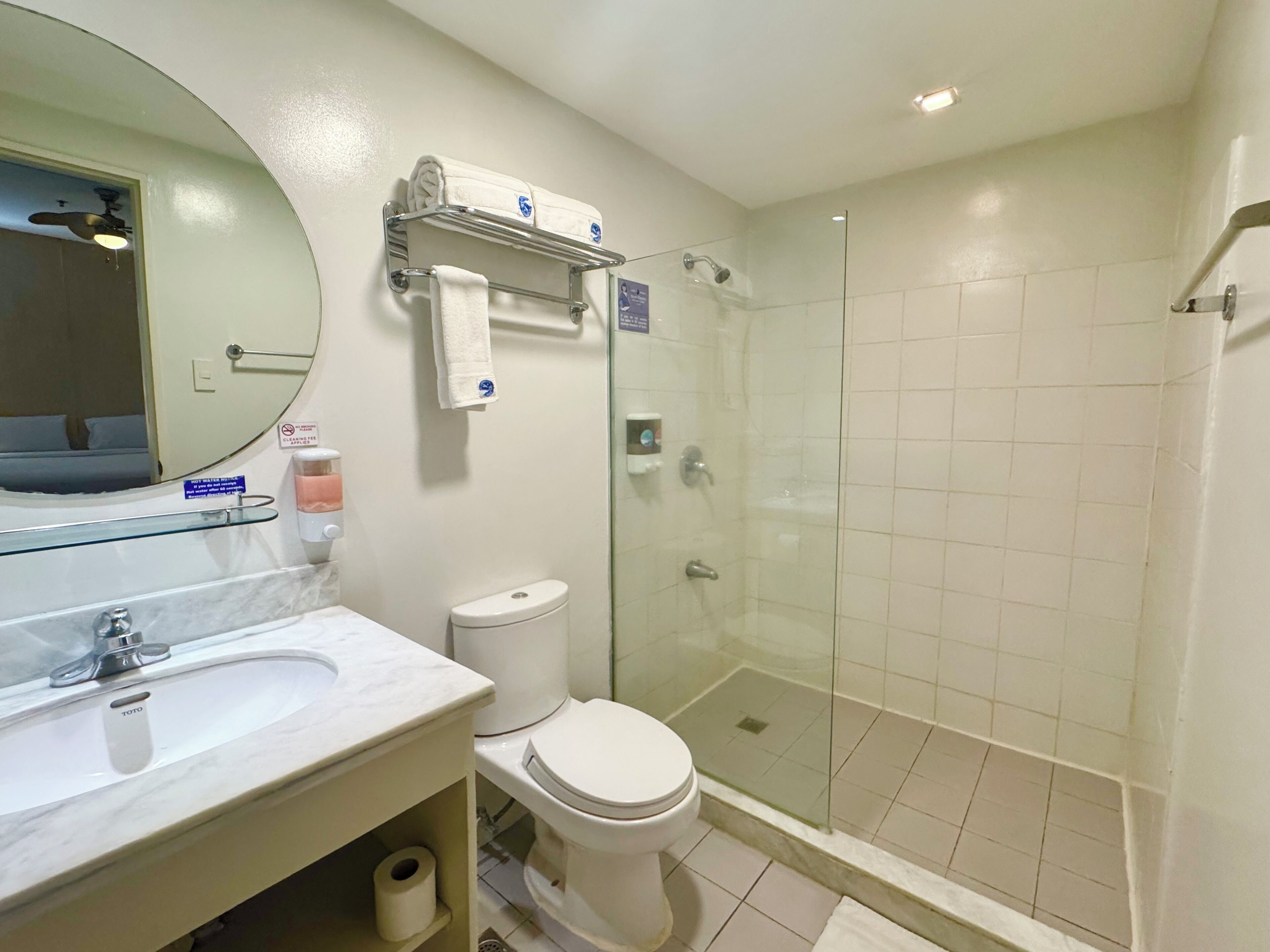 Un baño con lavamanos de mármol, inodoro, cabina de ducha de vidrio y espejo.