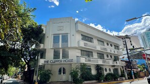 Un hotel de varios pisos llamado "The Clipper House", con fachada moderna, grandes ventanales y una entrada destacada.