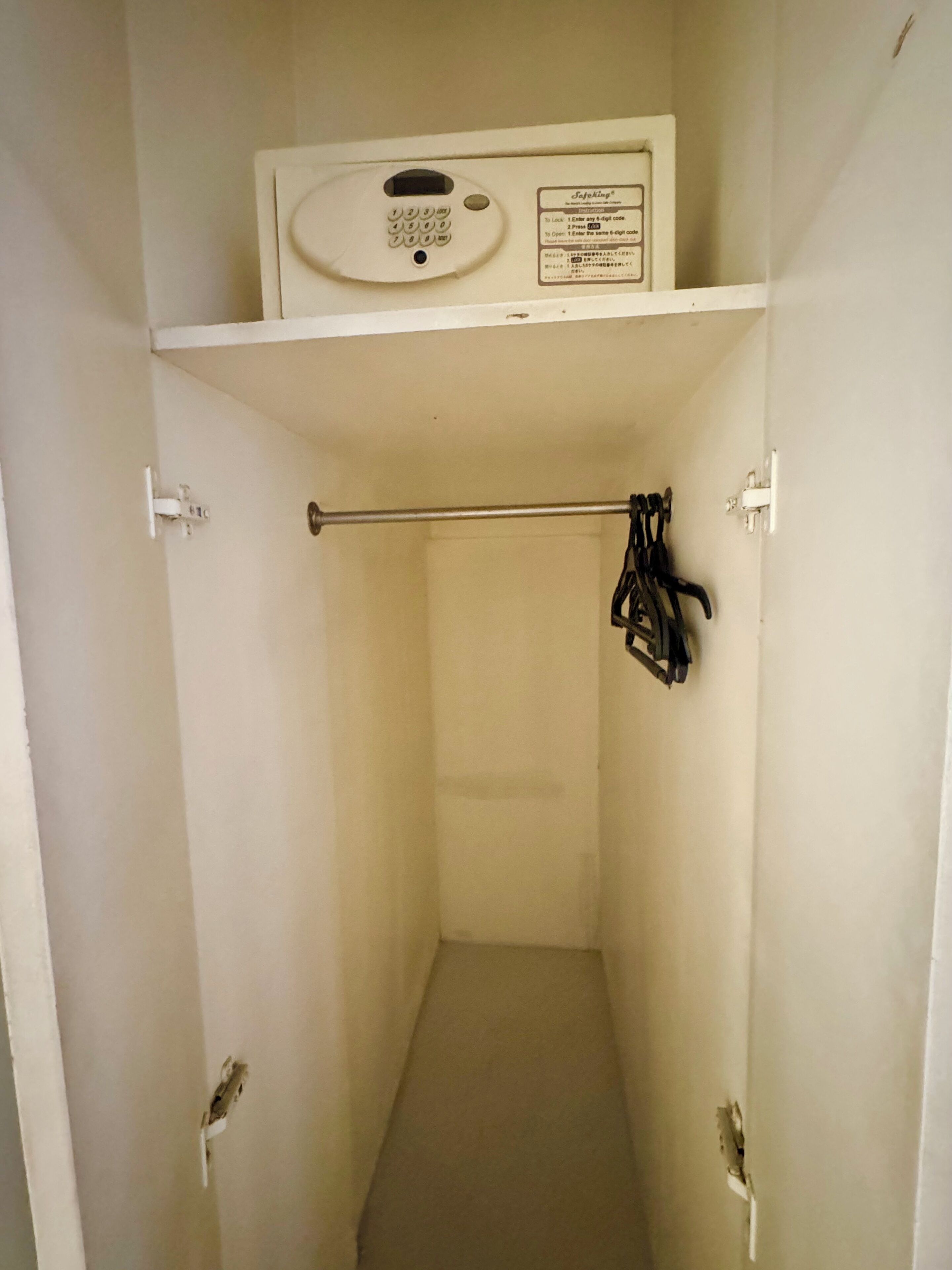 A small, narrow bathroom with a toilet, a towel rack, and a control panel above the toilet.