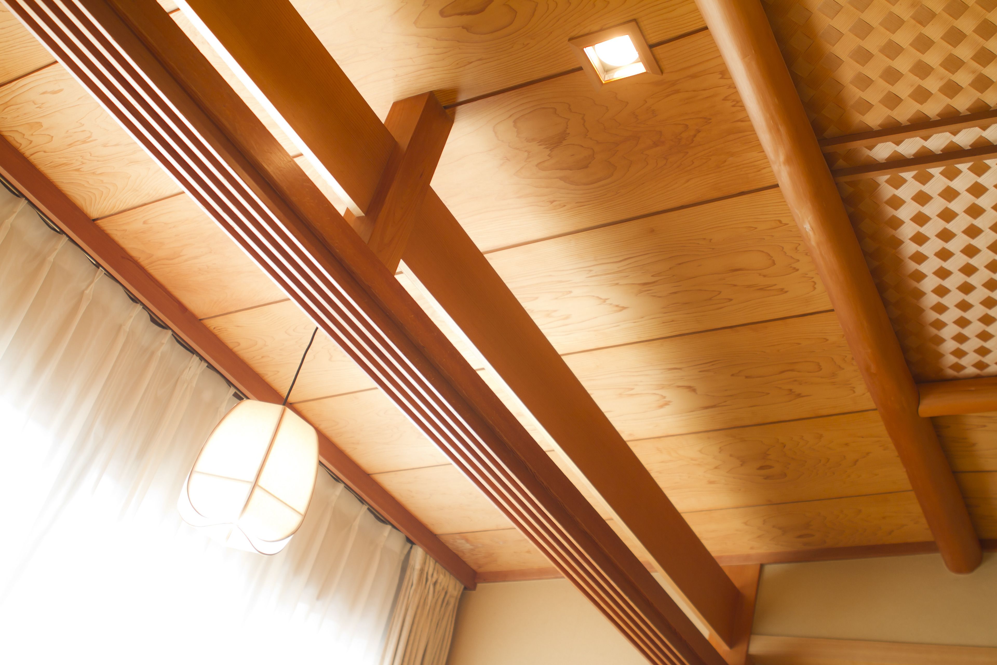 Un plafond en bois avec des poutres apparentes et un luminaire suspendu.